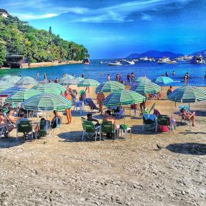 Dom Pedro 26 في غوارويا: مجموعة من الناس جالسين على شاطئ فيه مظلات