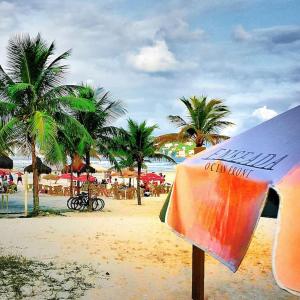 a surfboard on a beach with palm trees in the background at Dom Pedro 26 in Guarujá