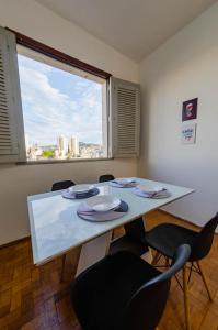 a dining room table with chairs and a large window at Apto 3qts centro - vista cartão postal in Belo Horizonte