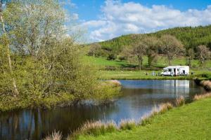 an rv is parked next to a river at A Homely Welsh Cottage on Heol Maelor in Coedpoeth