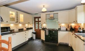 cocina con armarios blancos y estufa verde en Scandale Cottage en Ambleside