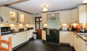 a kitchen with white cabinets and a green stove at Scandale Cottage in Ambleside