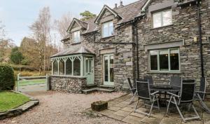 a stone house with a table and chairs in front of it at Scandale Cottage in Ambleside