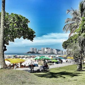a beach with tables and umbrellas and a city at Dom Pedro 55 in Guarujá