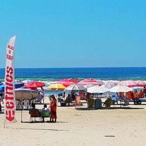 a beach with a bunch of umbrellas and people on the beach at Dom Pedro 55 in Guarujá