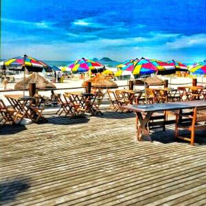 a group of tables and umbrellas on a beach at Dom Pedro 55 in Guarujá