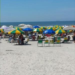a group of chairs and umbrellas on a beach at Dom Pedro 55 in Guarujá
