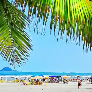 a beach with a crowd of people and umbrellas at Dom Pedro 55 in Guarujá