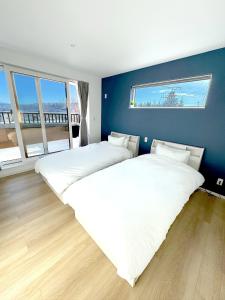 two beds in a bedroom with a blue wall at KOYO・YUKI in Furano