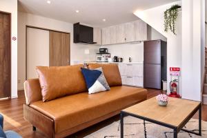 a living room with a brown couch and a kitchen at KOYO・YUKI in Furano
