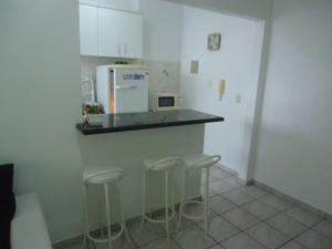 a kitchen with a counter with stools and a refrigerator at Dom Pedro 54 in Guarujá