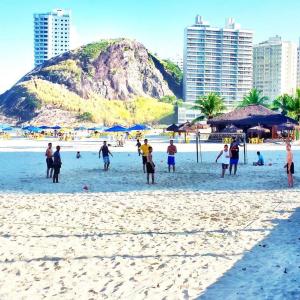 a group of people standing on a beach at Dom Pedro 54 in Guarujá