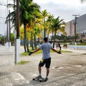 a man riding a skateboard down a street at Dom Pedro 54 in Guarujá