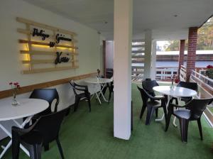 a dining room with white tables and black chairs at Pokoje Gościnne u Kasi in Międzywodzie