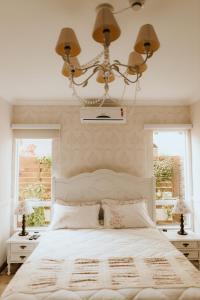 a bedroom with a bed with a chandelier and two windows at Pousada Paty´s Garden in Florianópolis