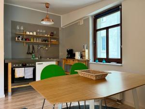 cocina con mesa de madera y sillas verdes en Hinterhaus Apartments, en Leipzig