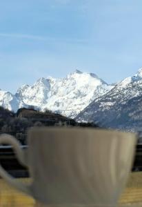 Una taza de café con montañas cubiertas de nieve en el fondo en Ayma5, en Aymavilles
