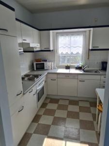 a kitchen with white cabinets and a checkered floor at Gemütliches Gästehaus in ruhiger Waldlage in Büdingen