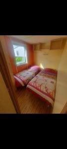 two beds in a room with a window at Mobilhome 6 personnes in Angles