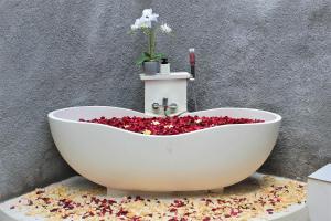 eine weiße Badewanne mit roten Blütenblättern in der Unterkunft Green Village Jungle Resort in Nusa Penida