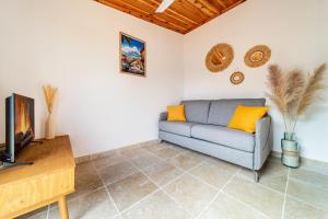 a living room with a couch and a tv at Bungalow L'escale de Takamaka in Saint-Benoît