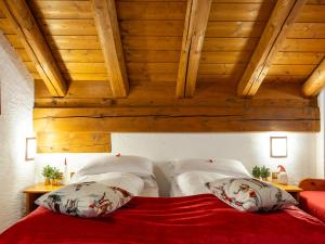 - une chambre avec un lit rouge et des plafonds en bois dans l'établissement Residence Monterosa, à Macugnaga