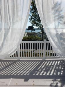 a white fence and a white curtain on a porch at Family Seaside Retreat Private Stay at 5-Star Rockley Holiday Park Poole in Poole