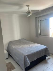 a bedroom with a bed and a ceiling fan at Apartamento na Praia das Asturias - Pé na Areia in Guarujá