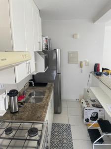 a kitchen with a stove and a refrigerator at Apartamento na Praia das Asturias - Pé na Areia in Guarujá