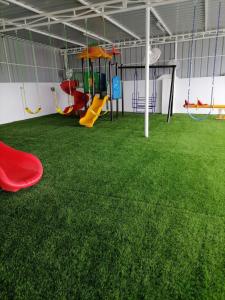 ein Zimmer mit einem Spielplatz mit grünem Gras in der Unterkunft Munaya Chalet 2 منايا شاليه 2 in Ḩayl Āl ‘Umayr