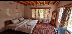 a bedroom with a bed and two windows at Rainbow Palace Pahalgam in Pahalgām