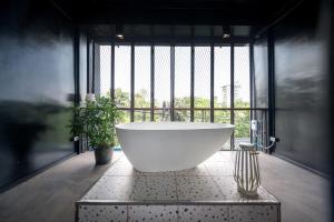 eine große Badewanne in einem Zimmer mit Fenster in der Unterkunft MIQ Ekkamai2 3BR Designer home Oval Bathtub 15pax in Bangkok
