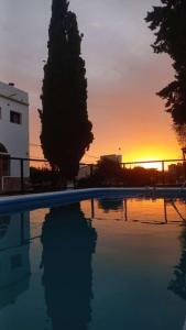 a swimming pool with the sunset in the background at Holâ Hotel in La Falda