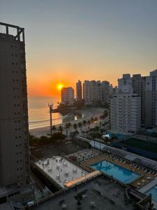 a view of a city with a beach and the sunset at Apartamento na Praia das Asturias - Pé na Areia in Guarujá