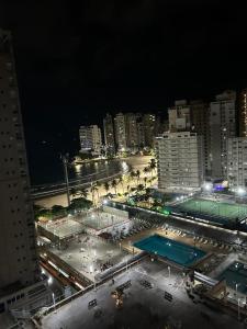 a night view of a parking lot in a city at Apartamento na Praia das Asturias - Pé na Areia in Guarujá