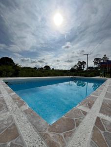 una piscina azul con un cielo nublado en FINCA HOTEL EL TURPIAL, en Quimbaya