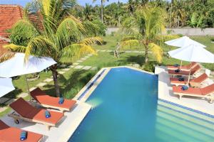 einen Blick über einen Pool mit Stühlen und Sonnenschirmen in der Unterkunft Green Village Jungle Resort in Nusa Penida