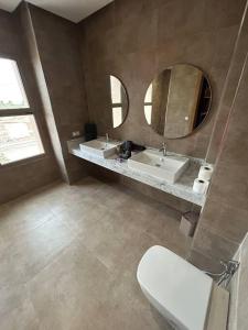 a bathroom with two sinks and a toilet and two mirrors at Villa California vue Atlas avec piscine chauffée in Marrakesh
