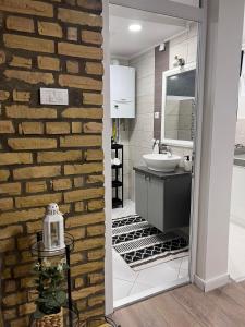 a bathroom with a sink and a brick wall at Guest House LILA in Sombor