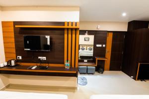 um quarto de hotel com uma secretária e uma televisão em Aheri Residency em Digha
