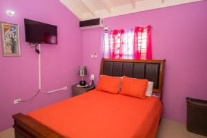 a bedroom with purple walls and a bed with orange pillows at Ocho Rios Drax Hall 1 Bedroom sleeps 1-3 persons in Saint Annʼs Bay