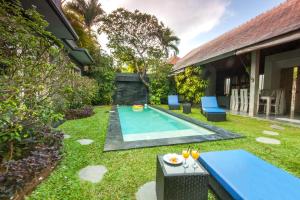 een achtertuin met een zwembad en gras bij Villa Jalak in Seminyak