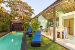 een zwembad in een achtertuin met een tafel en stoelen bij Villa Jalak in Seminyak