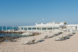 a group of chairs and umbrellas on a beach at La Peschiera in Monopoli