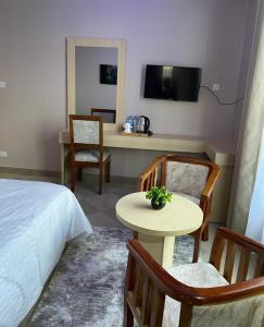 Habitación de hotel con cama, mesa y sillas en Rosa Hotels, en Dodoma