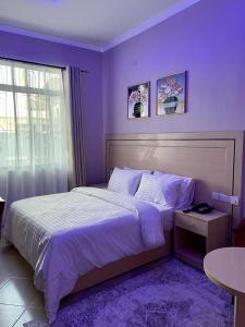 a bedroom with a large bed with purple walls at Rosa Hotels in Dodoma