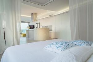a bedroom with a white bed and a kitchen at Marbell in Gandía +5 photos