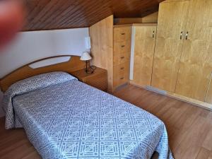a bedroom with a bed with a blue comforter and wooden cabinets at Allotjament amb encant a Tremp in Tremp