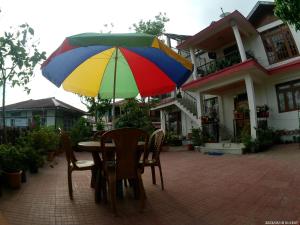 a table with a colorful umbrella in front of a house at Seyon Homestay in Kalimpong