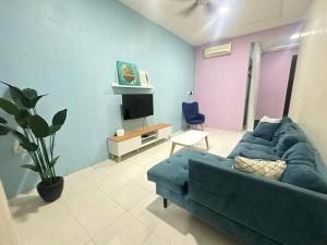 ein Wohnzimmer mit einem blauen Sofa und einem TV in der Unterkunft SH Homestay Perlis in Kangar
